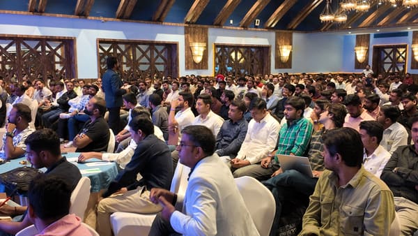 A large audience of men in a conference hall, listening to a speaker during a business seminar or presentation.